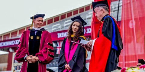 Jenna Mu in cap and gown receiving the Finnegan Award at Commencement